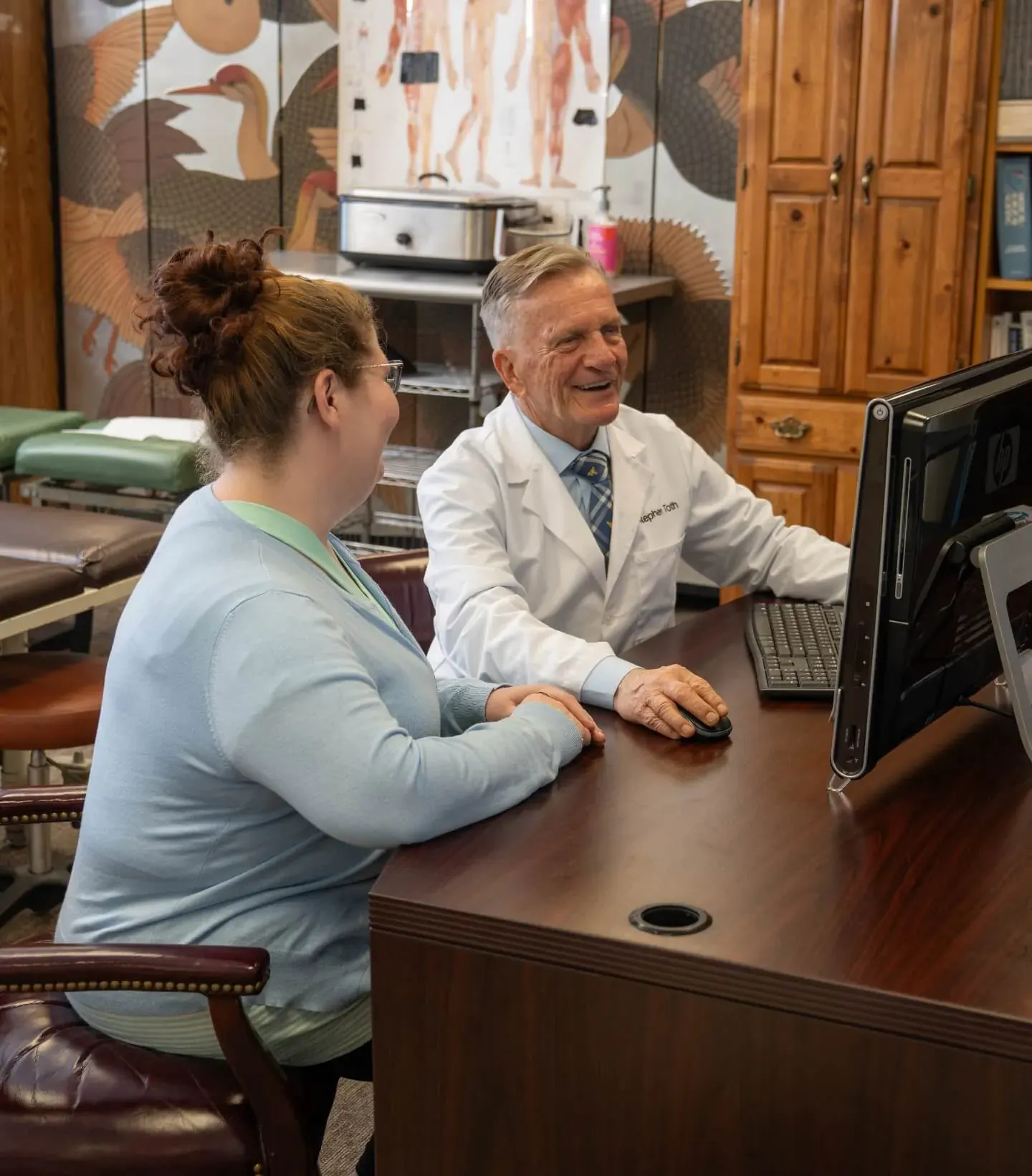 Dr. Toth at his desk talking through exam findings with a patient