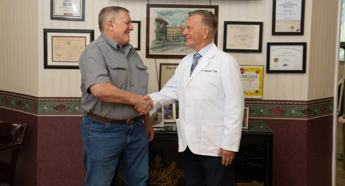Dr. Toth shaking hands with a patient in his office