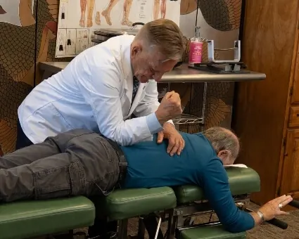 Dr. Stephen Toth adjusting a patient's lower back on the treatment table at his Morgantown office