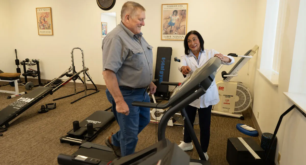 A patient exercising in the Toth Chiropractic rehab area with a staff member